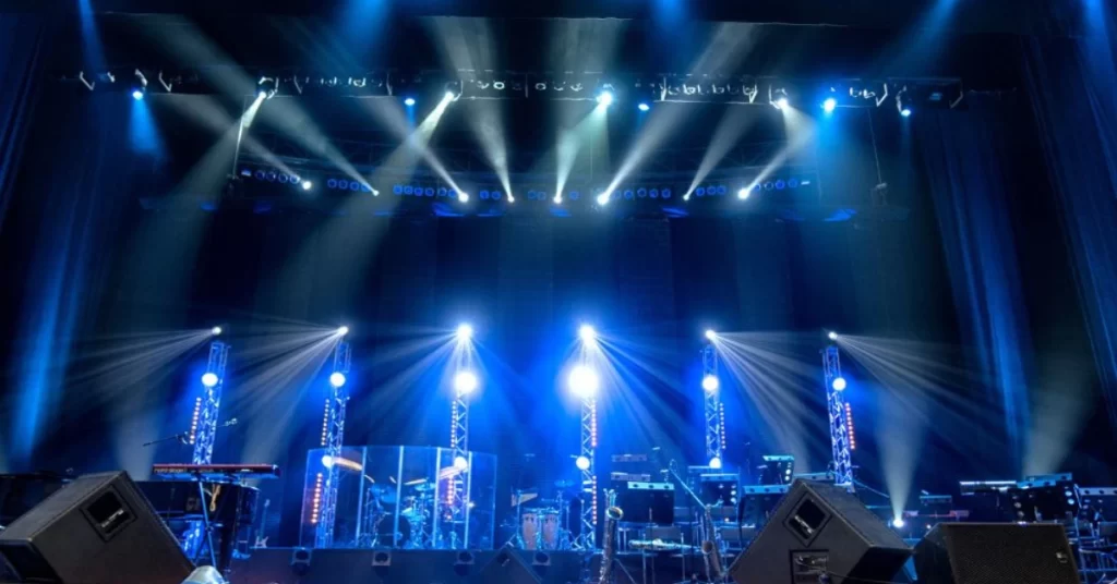 Empty concert stage setup with blue lighting and musical instruments